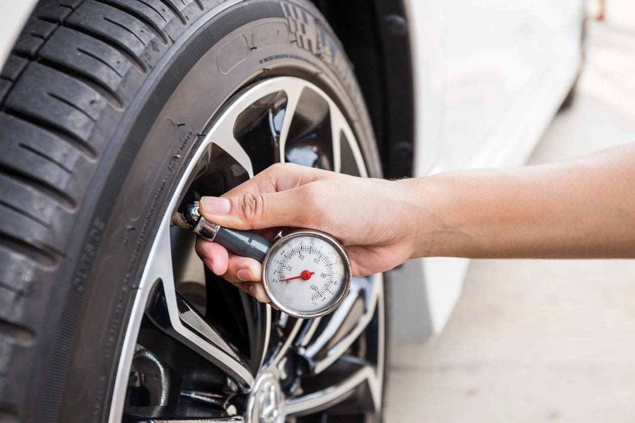 Measuring tire pressure with a gauge.