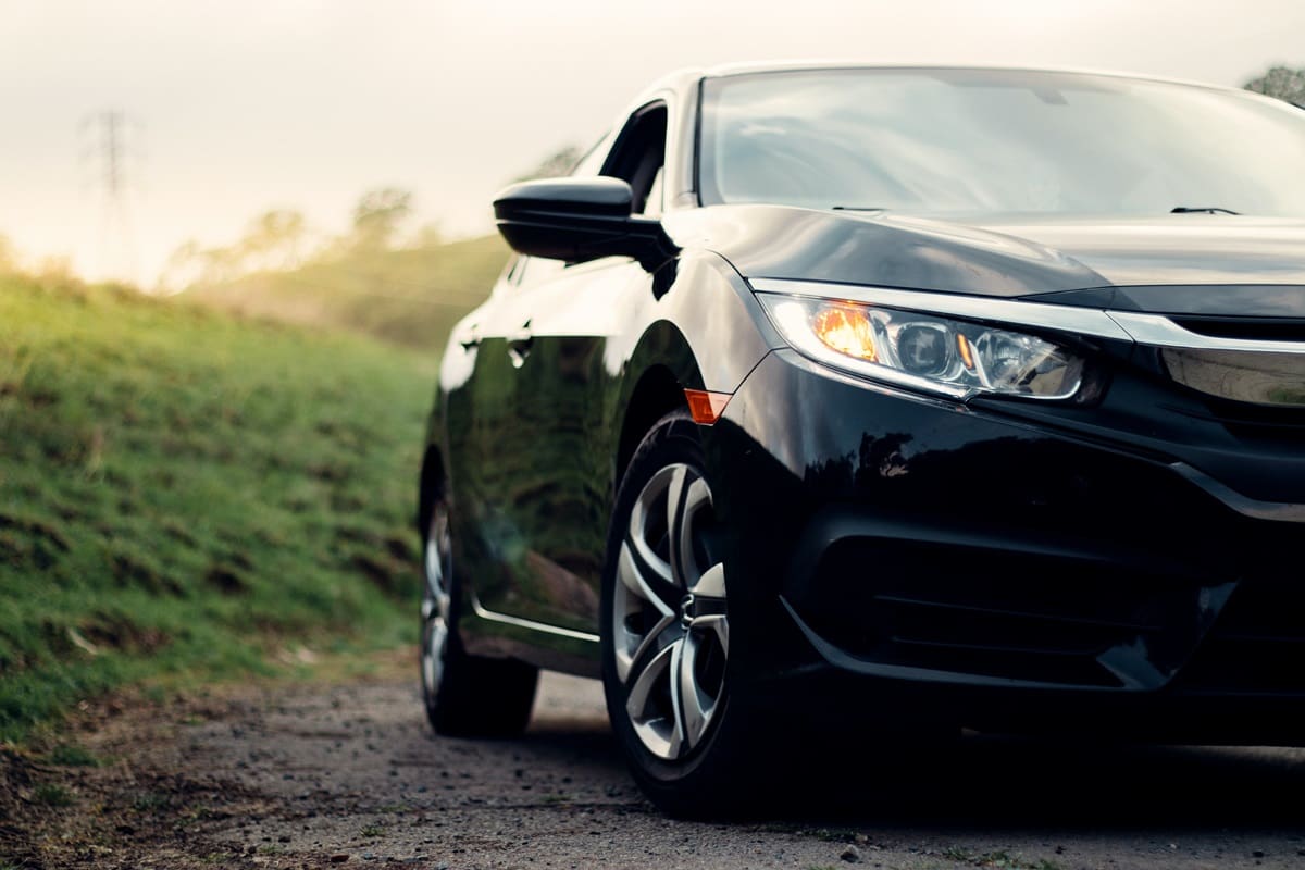 Black car on a grassy dirt path.